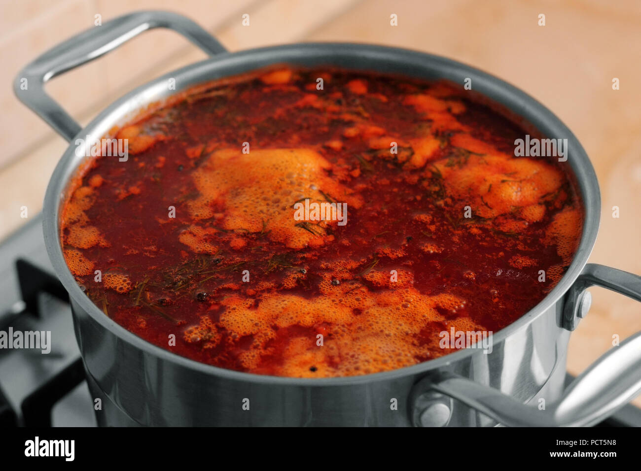 A pan of borsch cooking on a gas-stove photo Stock Photo