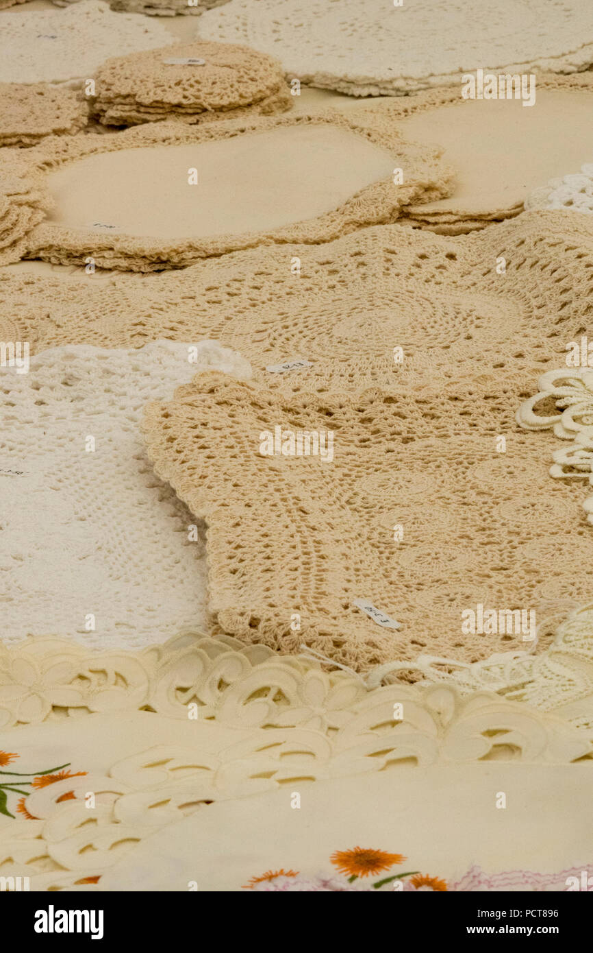 hand made lace doilies and table linen on display for sale at a craft fair. home made lace products Stock Photo