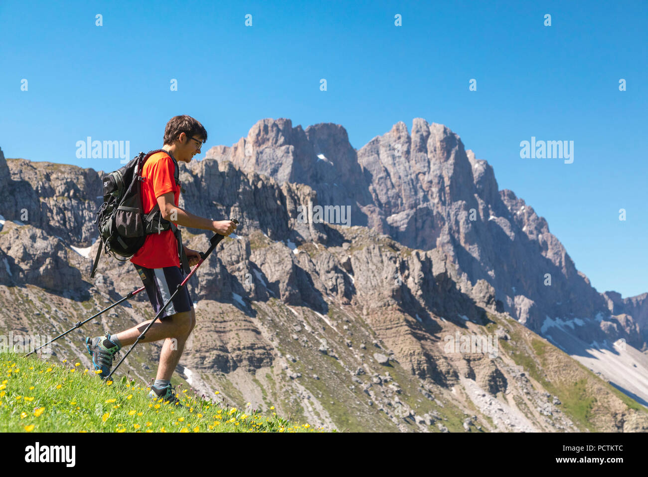 hiker walking in front of the Odle / Geisler walls, Funes Valley, Puez-Geisler Nature Park, Dolomites, Bolzano, South Tyrol, Italy Stock Photo