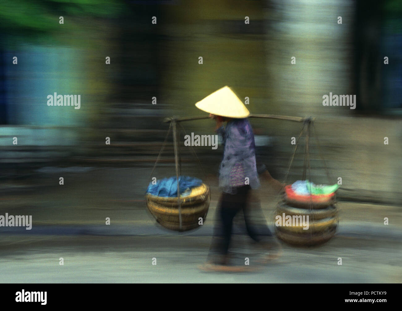 person with traditional hat carries loads, rush hour in Vietnam, Indochina Stock Photo