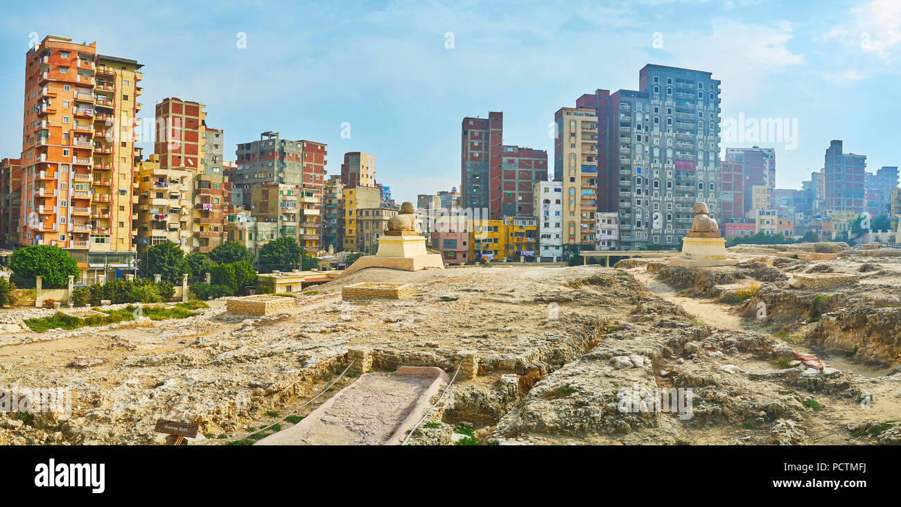 Panorama of Serapeum Temple ruins with two statues of sphinxes and residential high-rises on the distance, Amoud Al Sawari archaeological site, Alexan Stock Photo