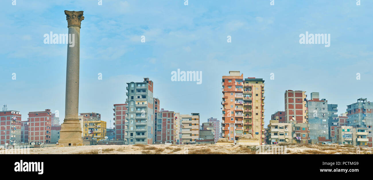 Panorama of Karmouz housing with tall Pompey's Pillar and Serapeum ruins on the foreground, Amoud Al Sawari archaeological site, Alexandria, Egypt. Stock Photo