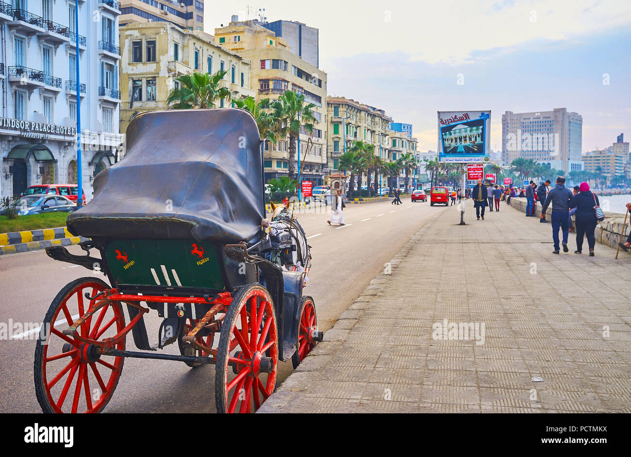 ALEXANDRIA, EGYPT - DECEMBER 18, 2017: Romantic ride on horse-drawn carriage along the sunset Corniche Avenue with a view on sea, palm trees, old mans Stock Photo