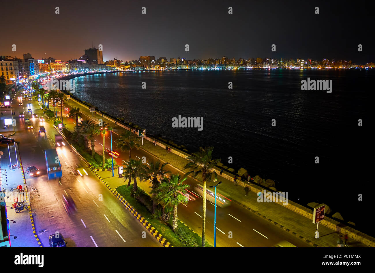 Observe the night Corniche promenade with bright city lights, dark waters of the sea and numerous cars, Alexandria, Egypt. Stock Photo