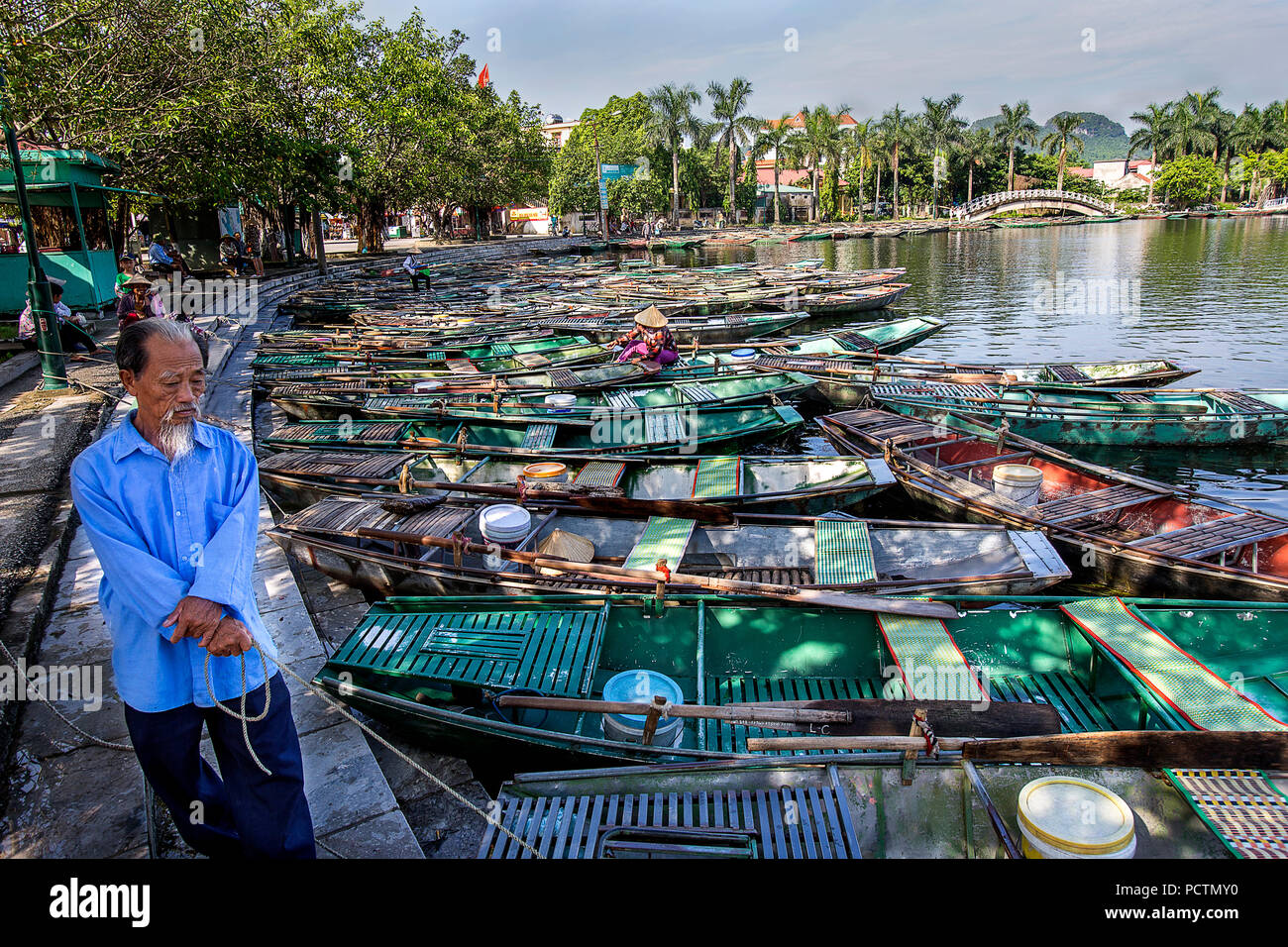 Asian man holds onto the boats in the morning light at Tam Coc, Vietnam Stock Photo