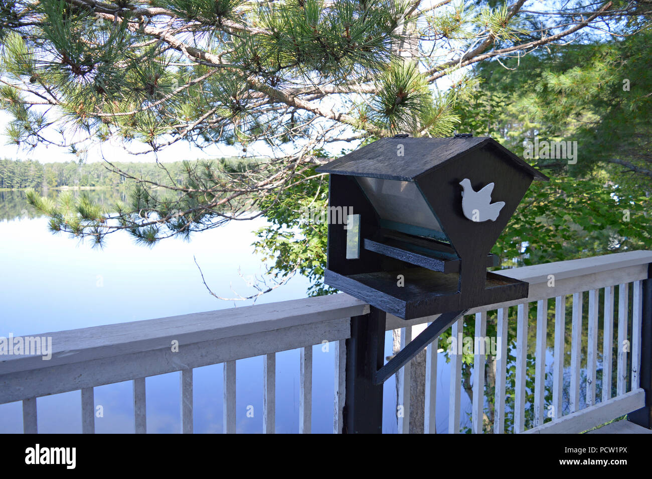 Bird house perched lake side on a calm, relaxing day at the cottage. Stock Photo