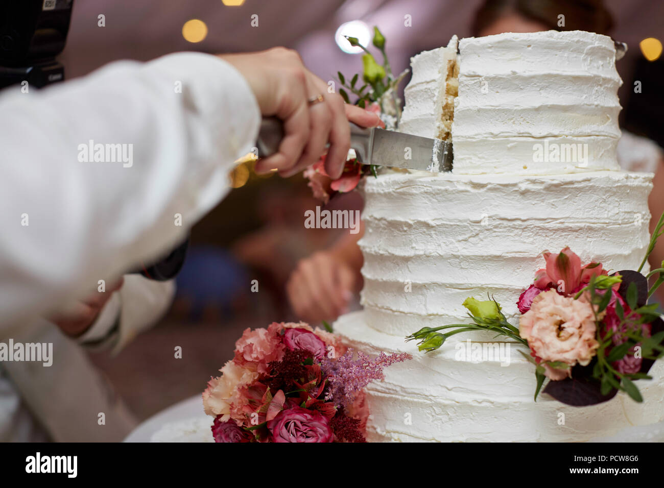 Bride and groom cutting elegant cake with roses Stock Photo