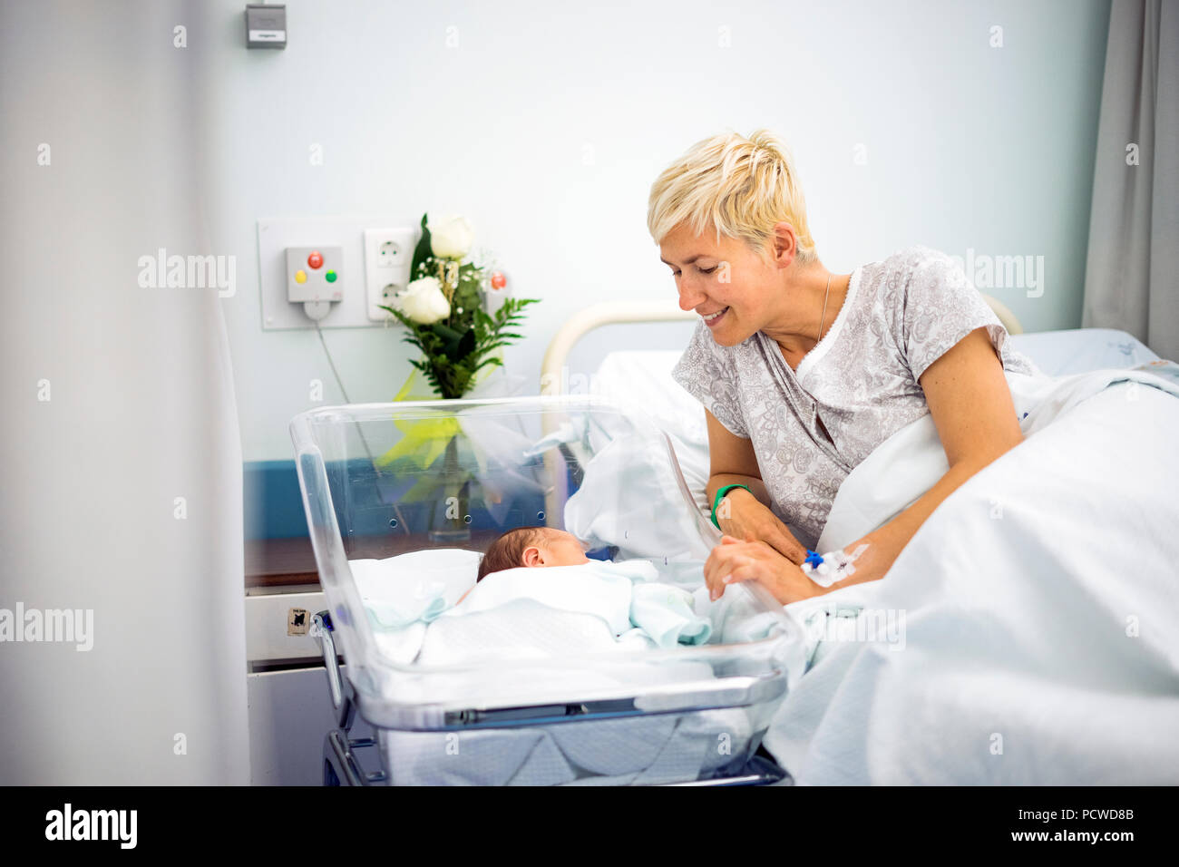 Mother looking with love at her newborn baby boy still in the hospital Stock Photo