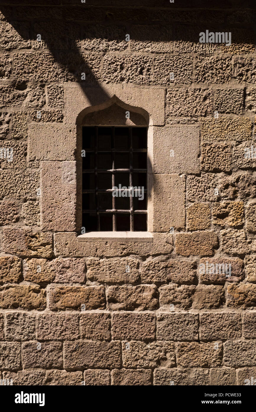 Barred window in a stone wall on Carrer Bisbe, Barri Gotic, Gothic Quarter, Barcelona, Spain Stock Photo