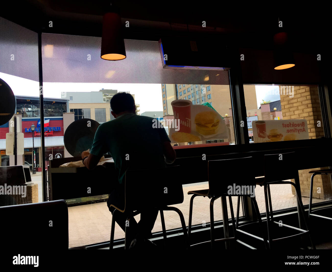 A man sitting by himself at a counter in a cafe looking out through a big picture window, Ontario, Canada. Watch the world go by. Solitude. Alone. Me. Stock Photo