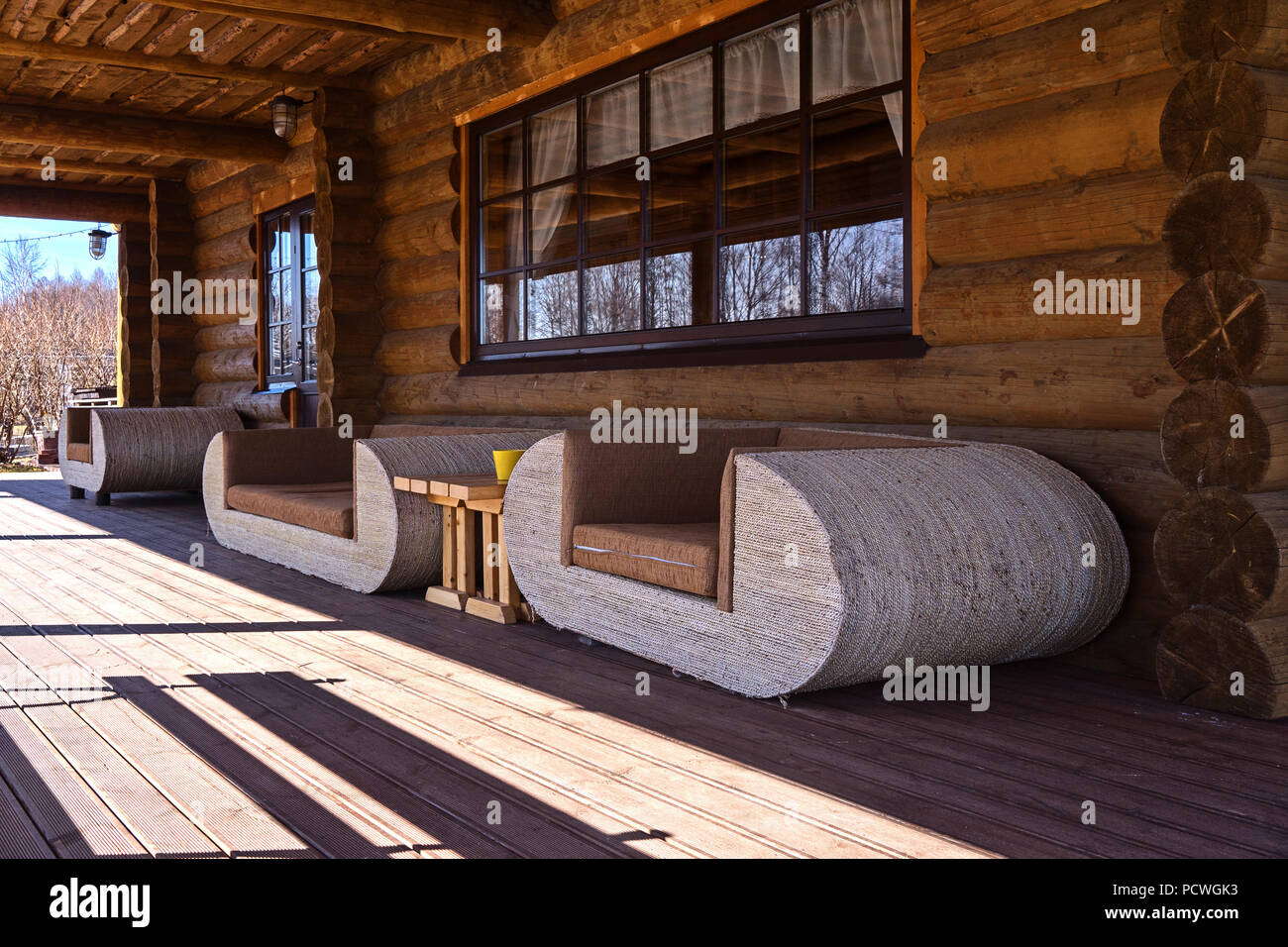 View of white sofas on log house terrace. Concept of ecological design