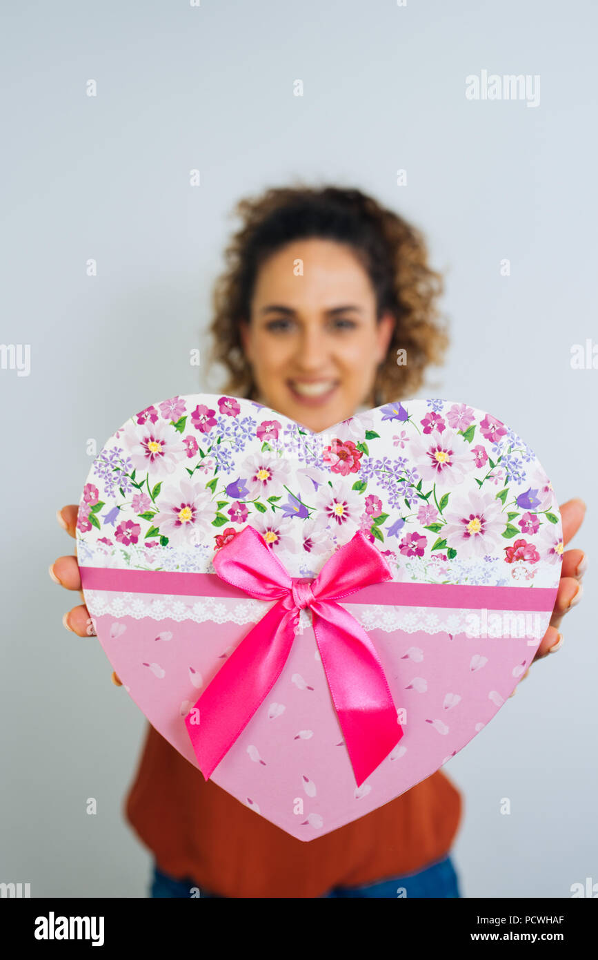 Attractive Curly Long Haired Woman Is Holding A Heart Shaped Box With Ribbon Isolated On White Background Stock Photo