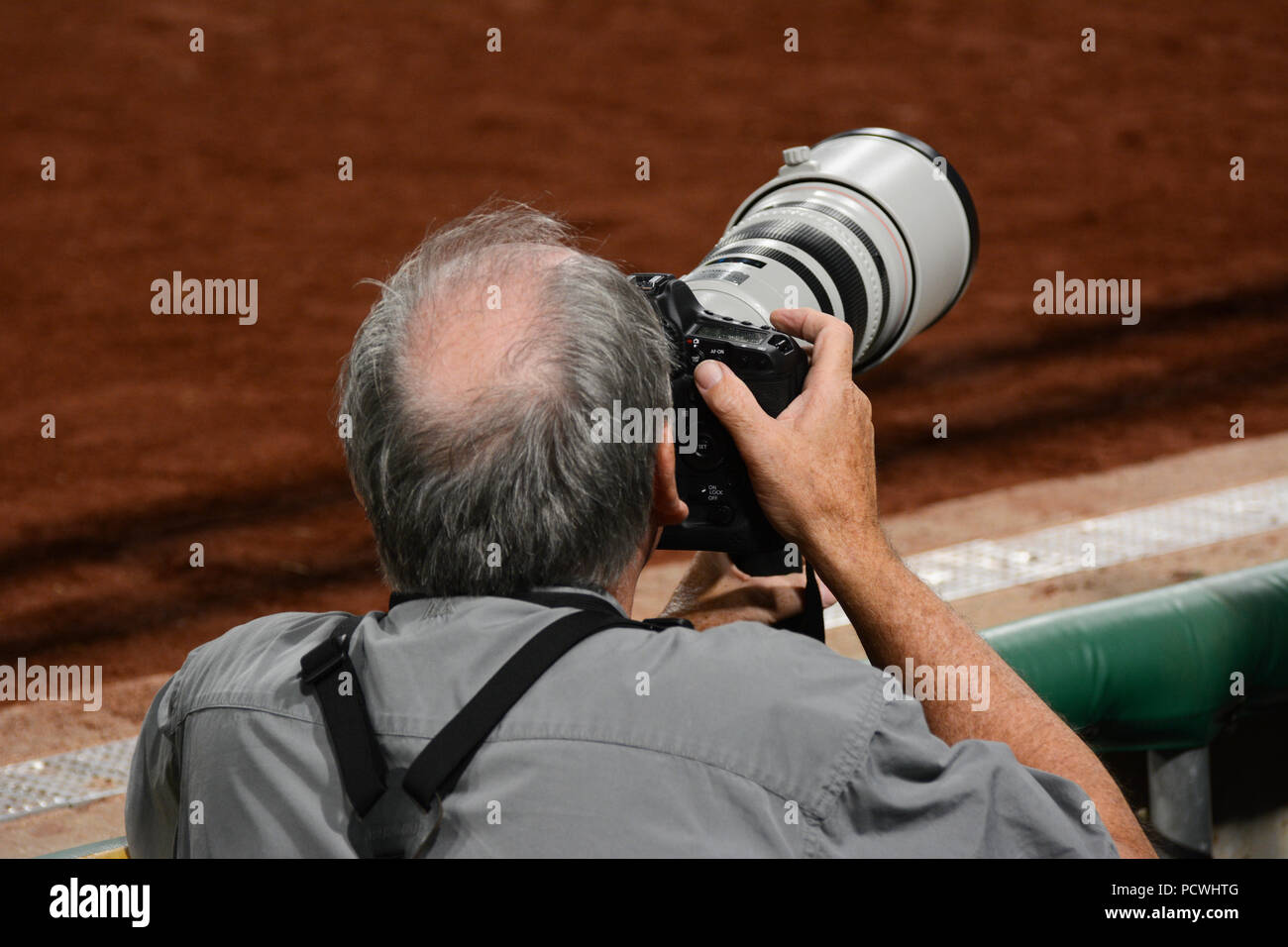 A professional sports photographer with a long telephoto lens focuses on the action at an MLB baseball game Stock Photo