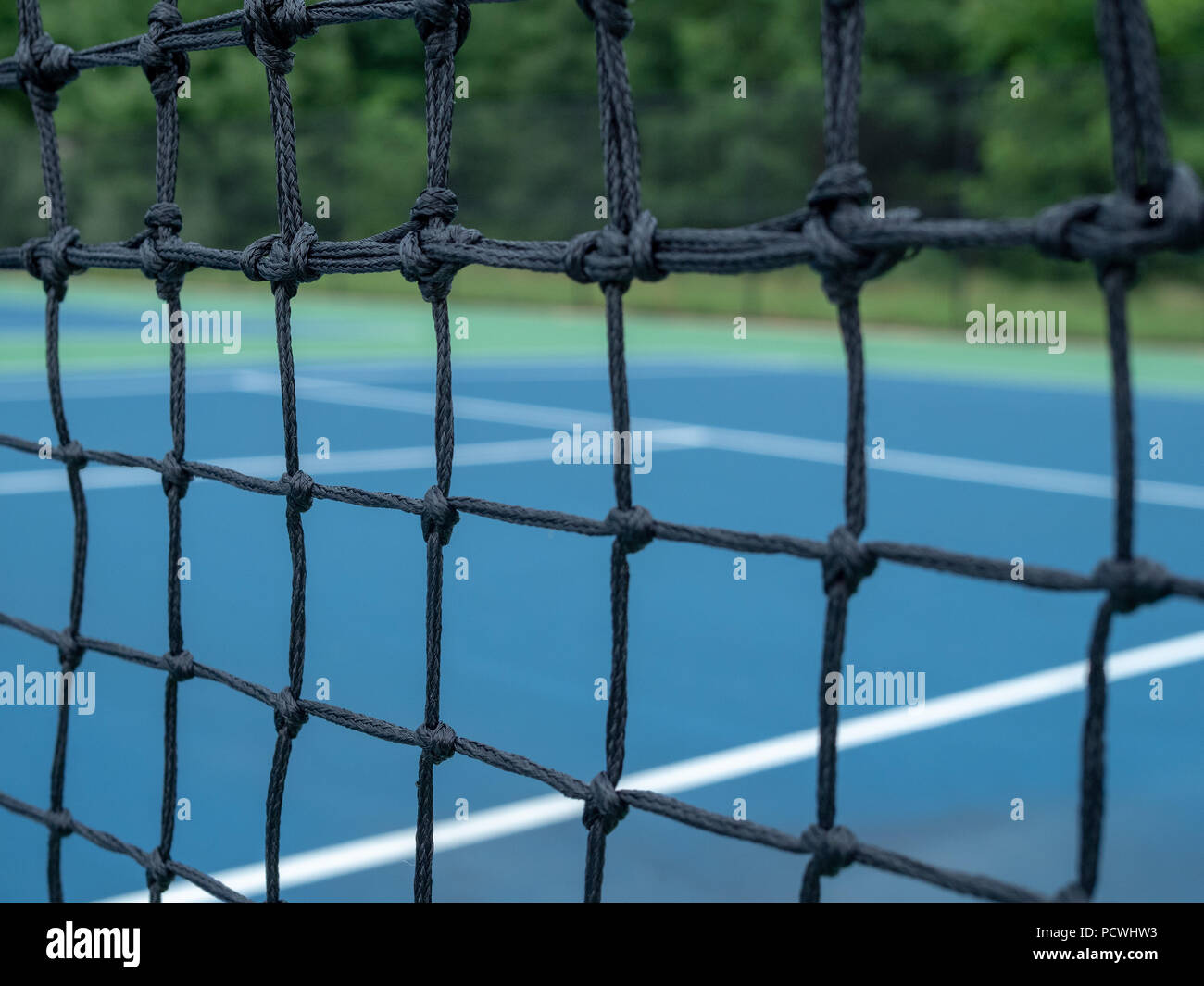 Zoomed view of tennis court net mesh with blurry courts in background