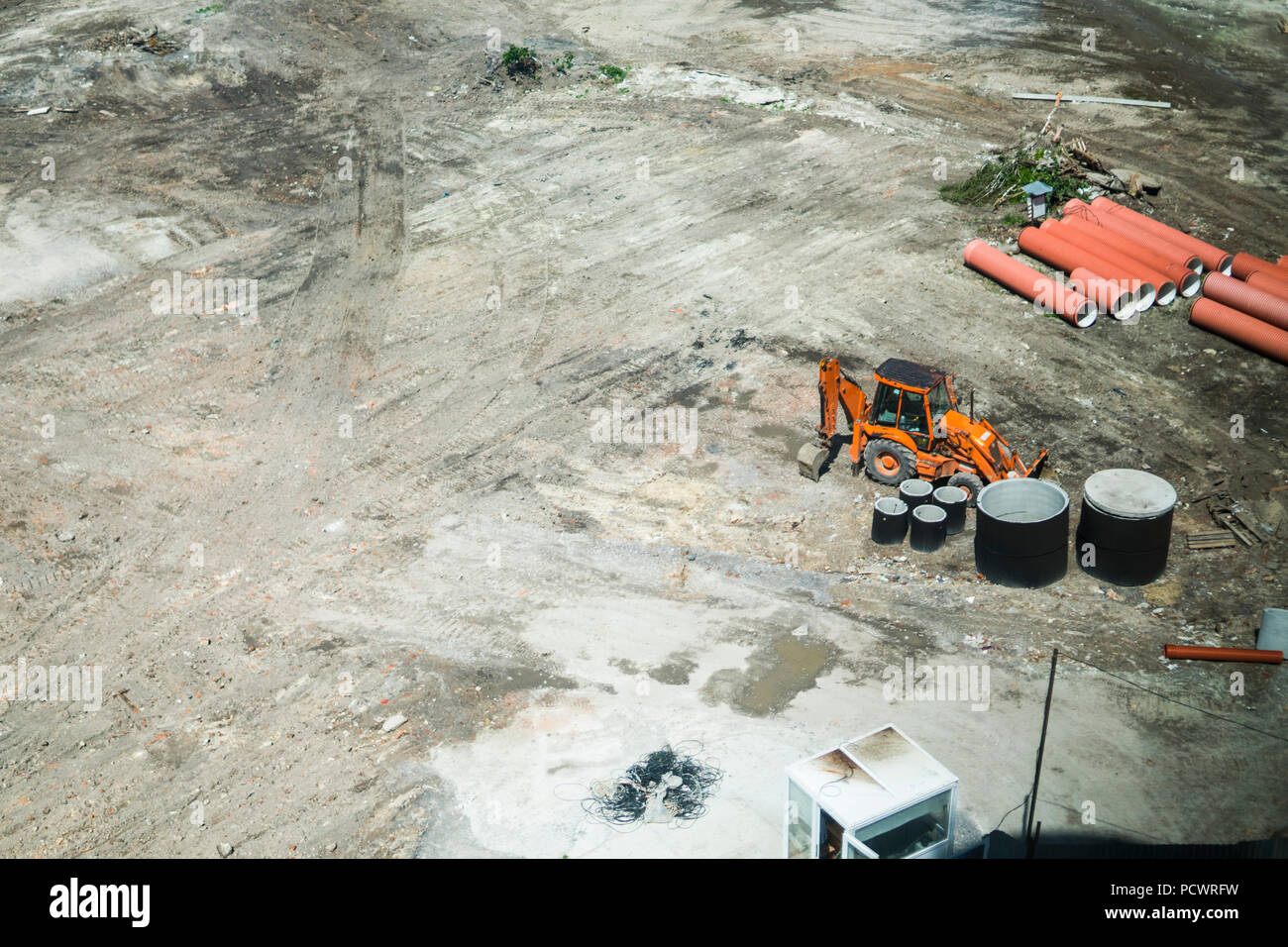 Orange excavator standing on a ground during construction of a new building in the city area. Aerial view on a construction building place. Construction machinery Stock Photo
