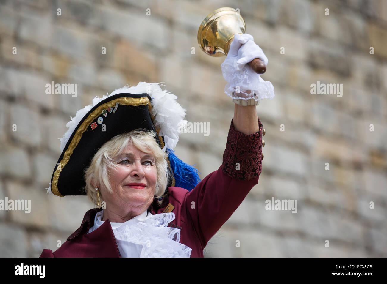 Windsor, UK. 4th August, 2018. Jackie Edwards, Town Crier of Kingsteignton, takes part in the Ancient and Honourable Guild of Town Criers (AHGTC) National Championship beneath the walls of Windsor Castle. Forty town criers from across the UK and two from Australia compete in two rounds of crying, the first a home cry scored on diction, inflection, clarity and volume and the second a cry on the topic of 'A Celebration’. Credit: Mark Kerrison/Alamy Live News Stock Photo