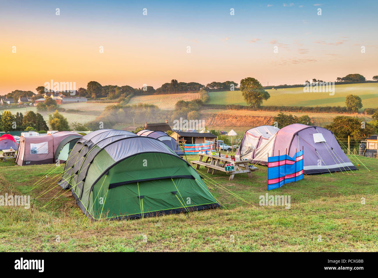 Devon, UK. 5 August 2018.  After a mild cool night, the early morning mist clears as the sun rises over the picturesque little campsite of Broad Park near Bideford in North Devon. Credit: Terry Mathews/Alamy Live News Stock Photo