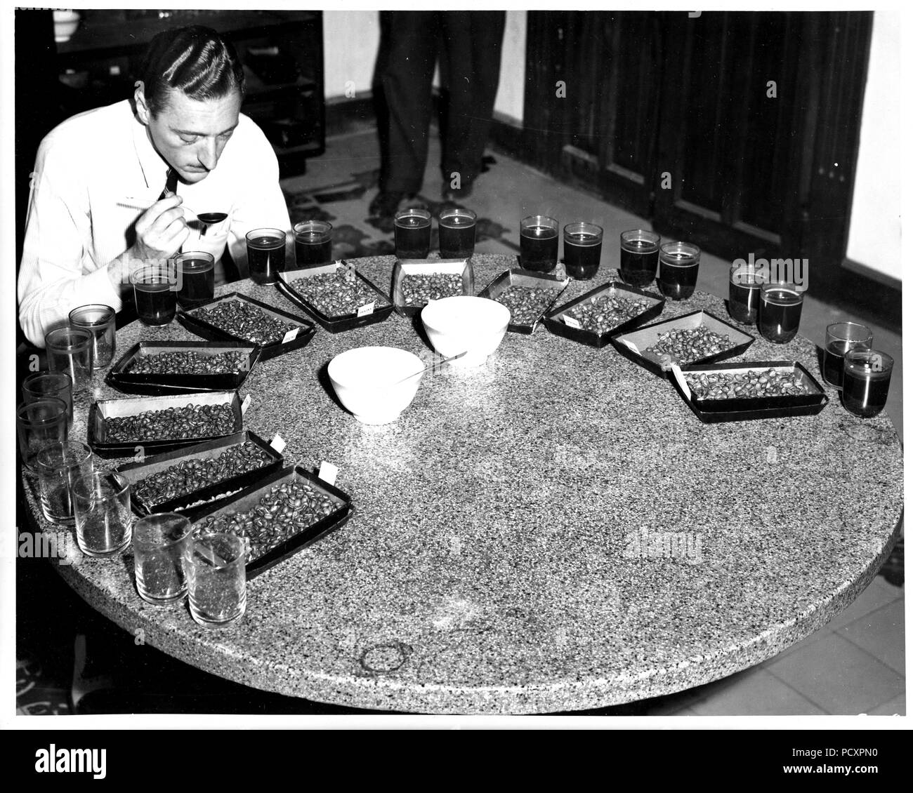 Coffee samples from various areas are being tested for taste and aroma by Sr. Aldo Cabella. Oficina Central de Cafe, Guatemala City, Guatemala.1947 Stock Photo