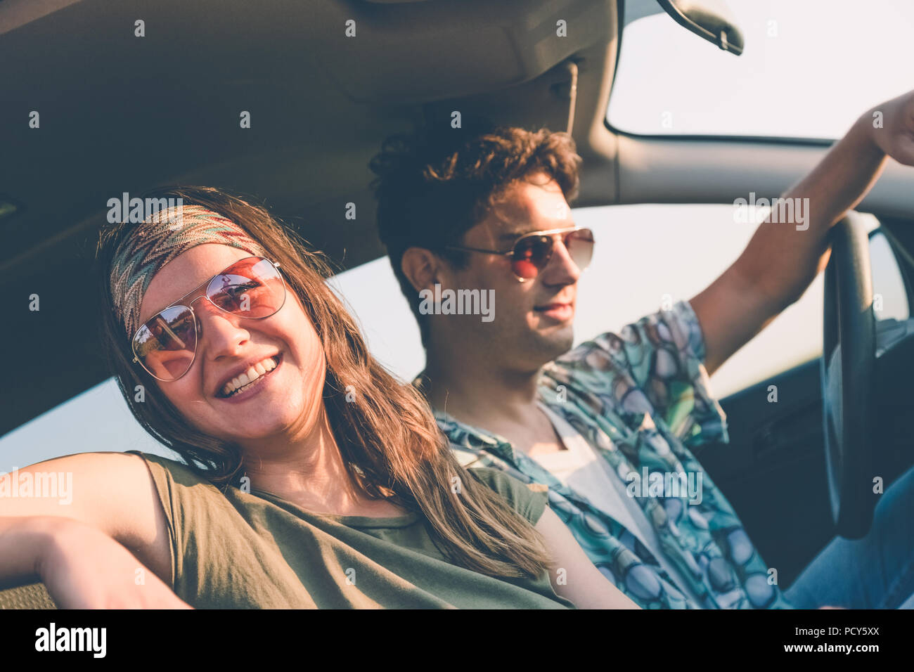 Side view of beautiful couple in car on their summer vacation road trip ...