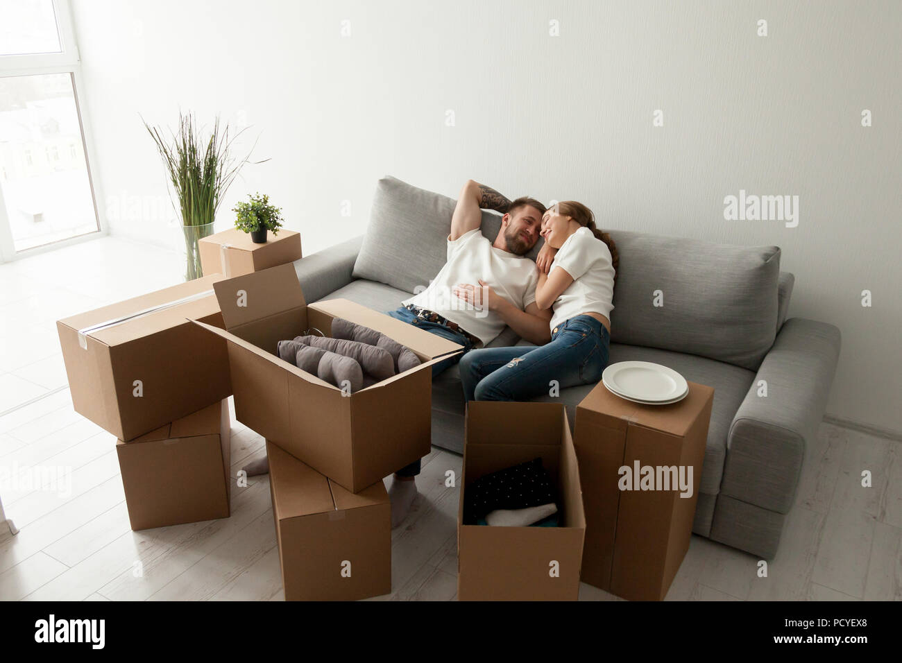 Loving husband lying together on sofa in first shared flat Stock Photo