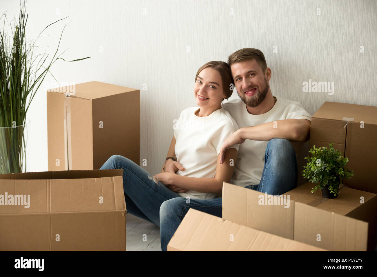 Portrait of millennial couple sitting on floor of first home Stock Photo
