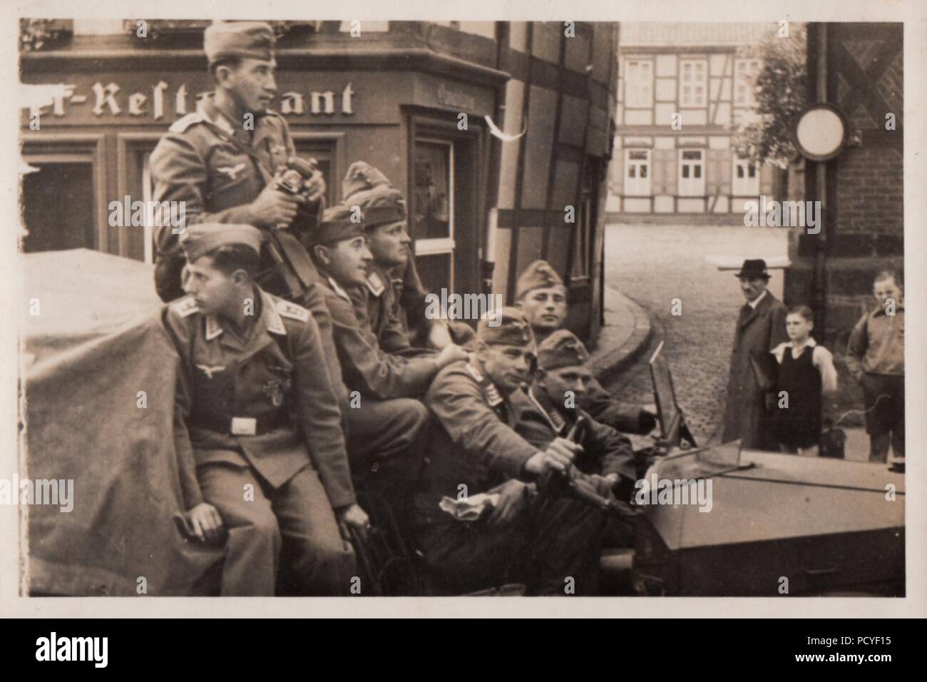 Image from the photo album of Oberfeldwebel Gotthilf Benseler of 9. Staffel, Kampfgeschwader 3: Oberfeldwebel Gotthilf Benseler (in middle of back row, looking to his front) and fellow Luftwaffe airmen drive through a German town in an open truck in 1941. Stock Photo