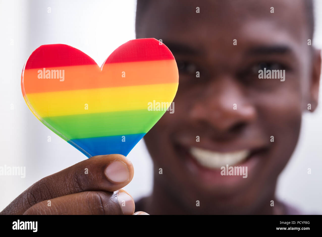 Smiling Man Holding Rainbow Heart In His Hand Against White Background ...