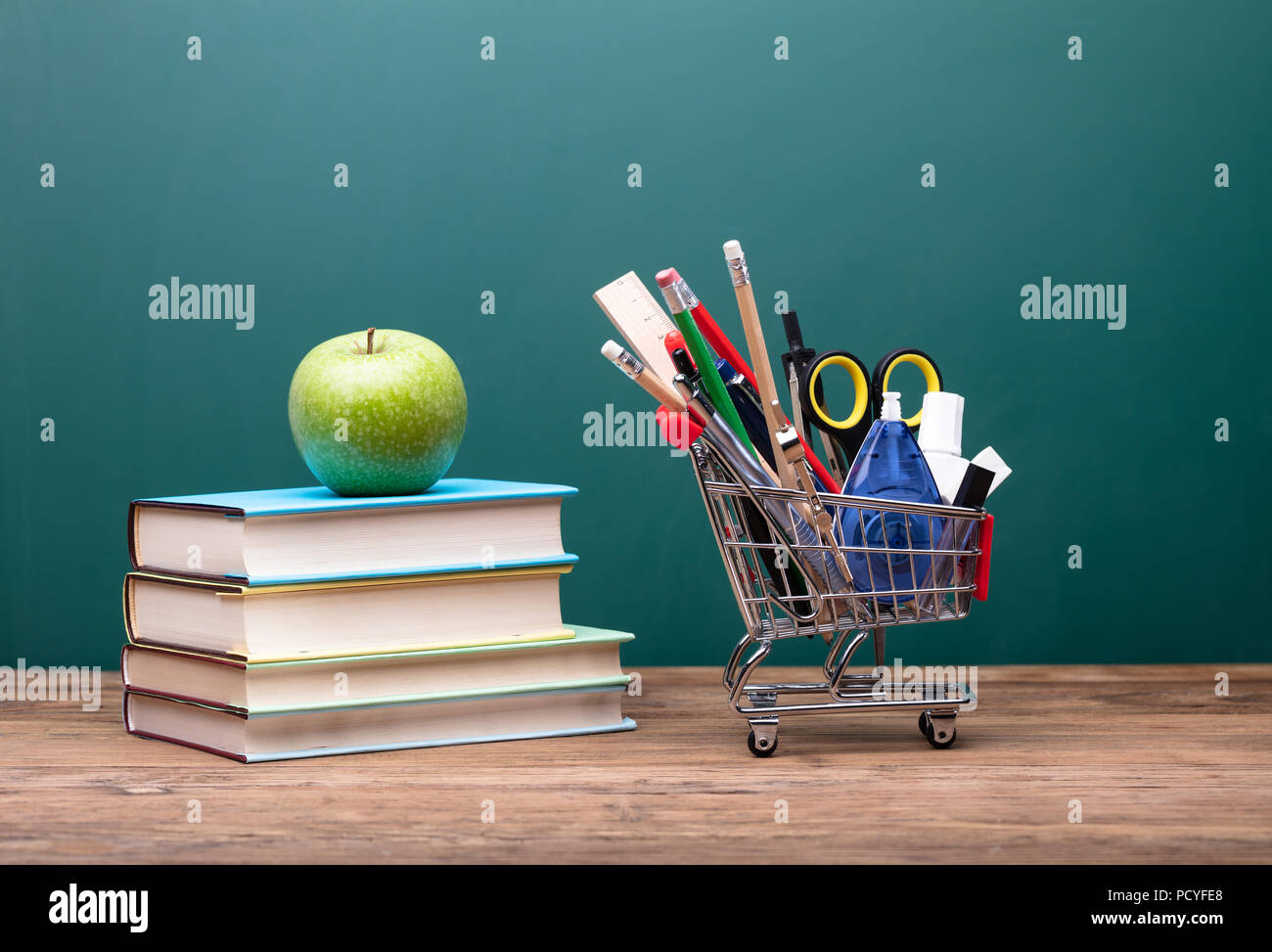 Stationery Cart Near Stack Of Books With Apple On Wooden Desk Stock Photo Alamy