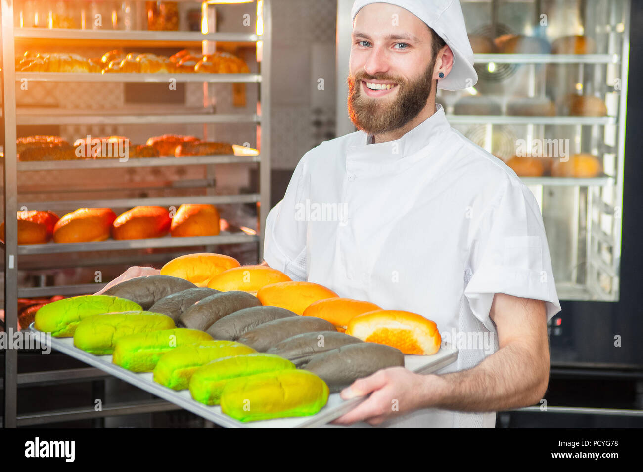 Cheerful young man baker standing at bakery holding bread Stock Photo by  vadymvdrobot