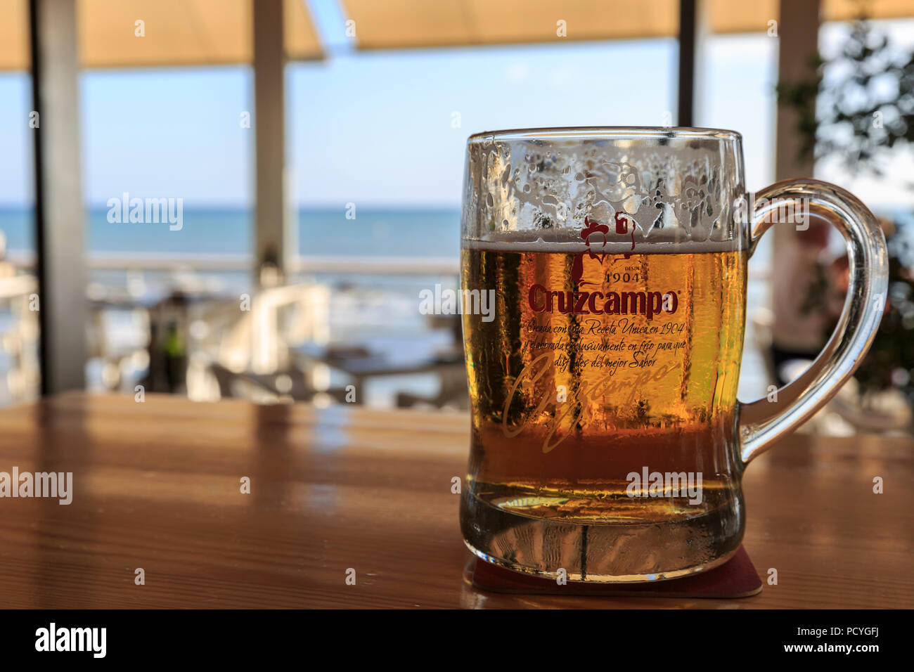 A drink stands on the bar of a chiringuito (beach bar) on the Costa del Sol, Spain, with the Mediterranean in the background Stock Photo