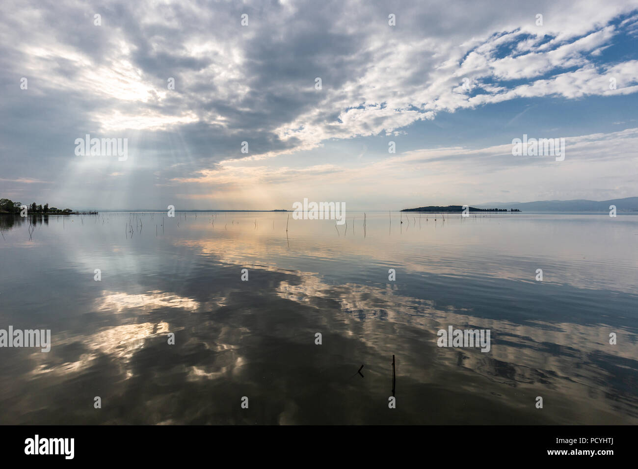 Perfectly symmetric and spectacular view of a lake, with clouds, sky and sun rays reflecting on water Stock Photo