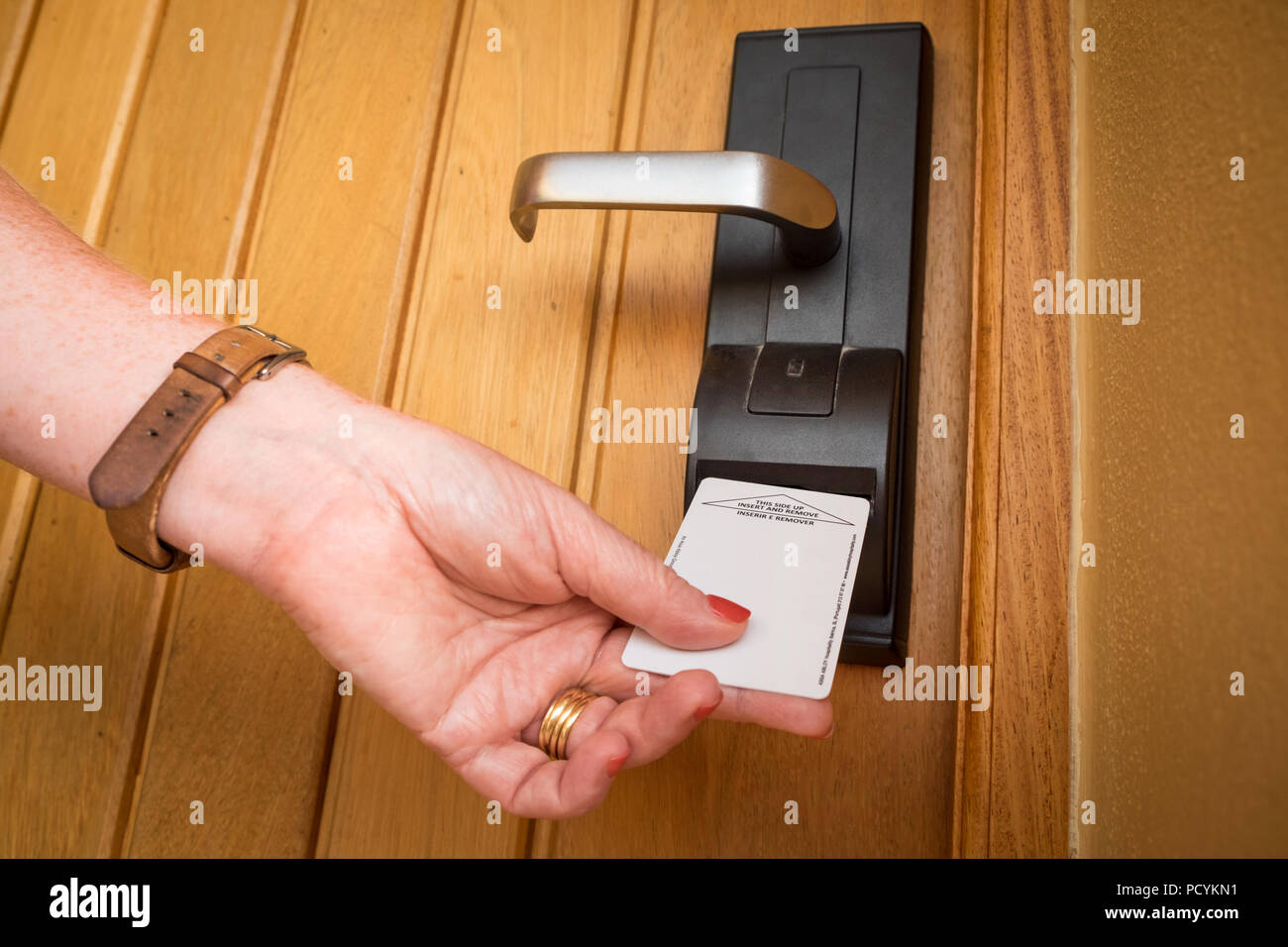 A woman entering a hotel room using an electric key card Stock Photo