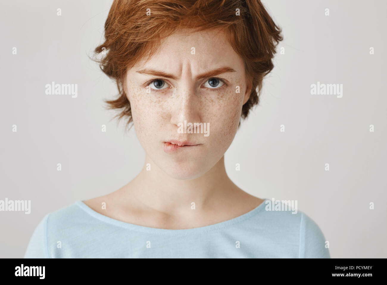 Close-up portrait of attractive angry redhead female looking from under  forehead with frowned eyebrows and sucked lips, being offended or  irritated, s Stock Photo - Alamy