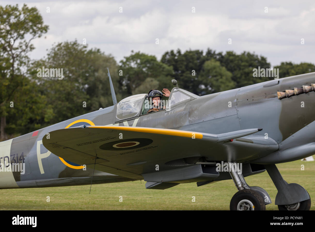 Side view of a historic RAF Spitfire aeroplane on the ground with the pilot waving Stock Photo