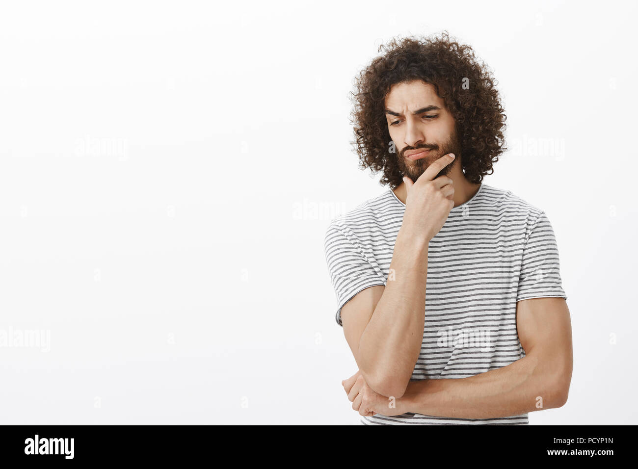 Studio Shot Of Doubtful Focused Adult Bearded Man With Dark