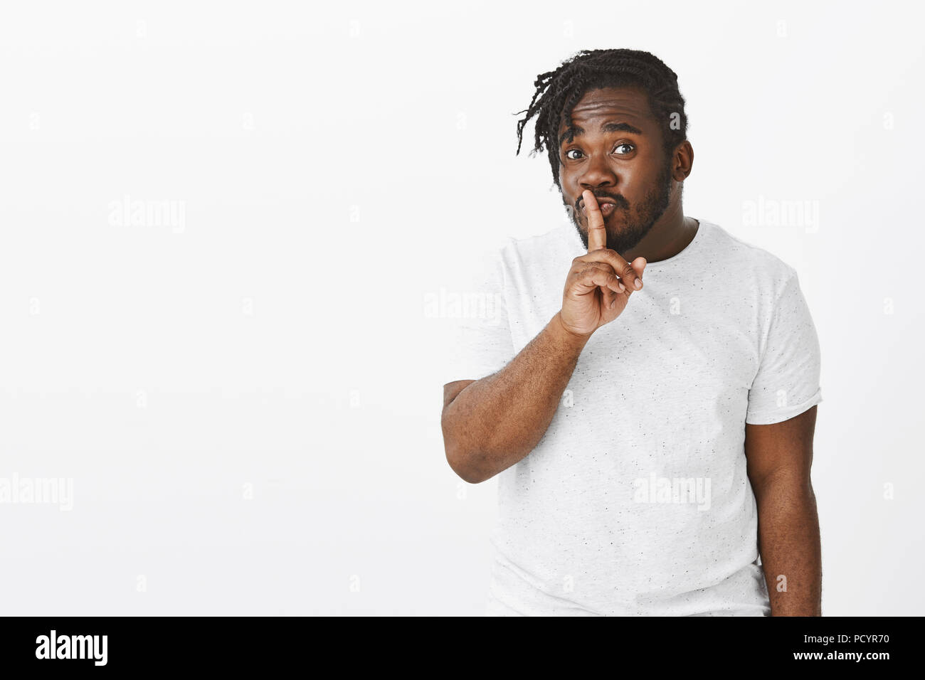 Flirty friendly african-american male with beard, making cute face while  saying shh and showing shush gesture with index finger over mouth, keeping  se Stock Photo - Alamy