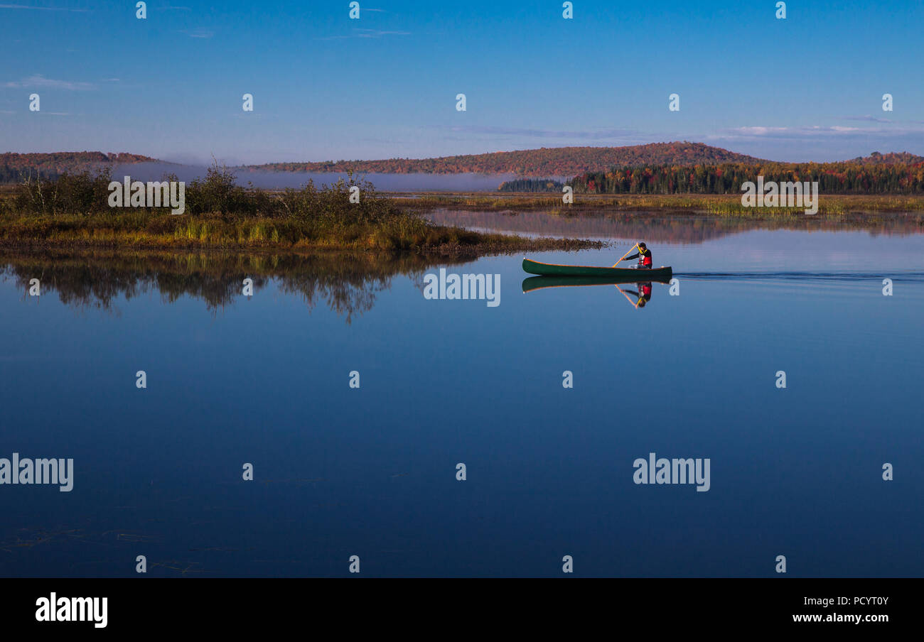 Man paddling a Chestnut canoe on the Eel River backwater in Benton, New Brunswick, Canada on a beautiful fall morning. Stock Photo