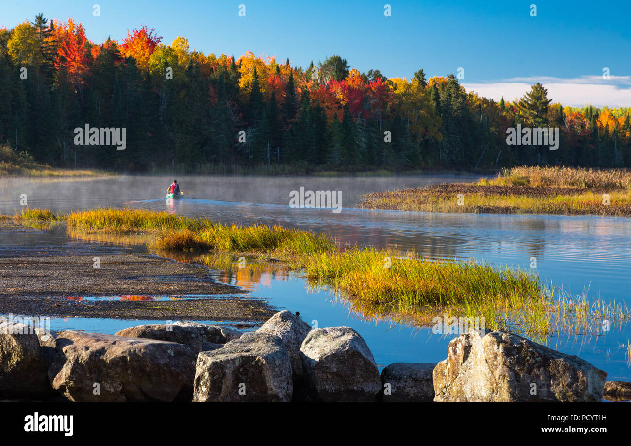 Man paddling a Chestnut canoe on the Eel River backwater in Benton, New Brunswick, Canada on a beautiful fall morning. Stock Photo
