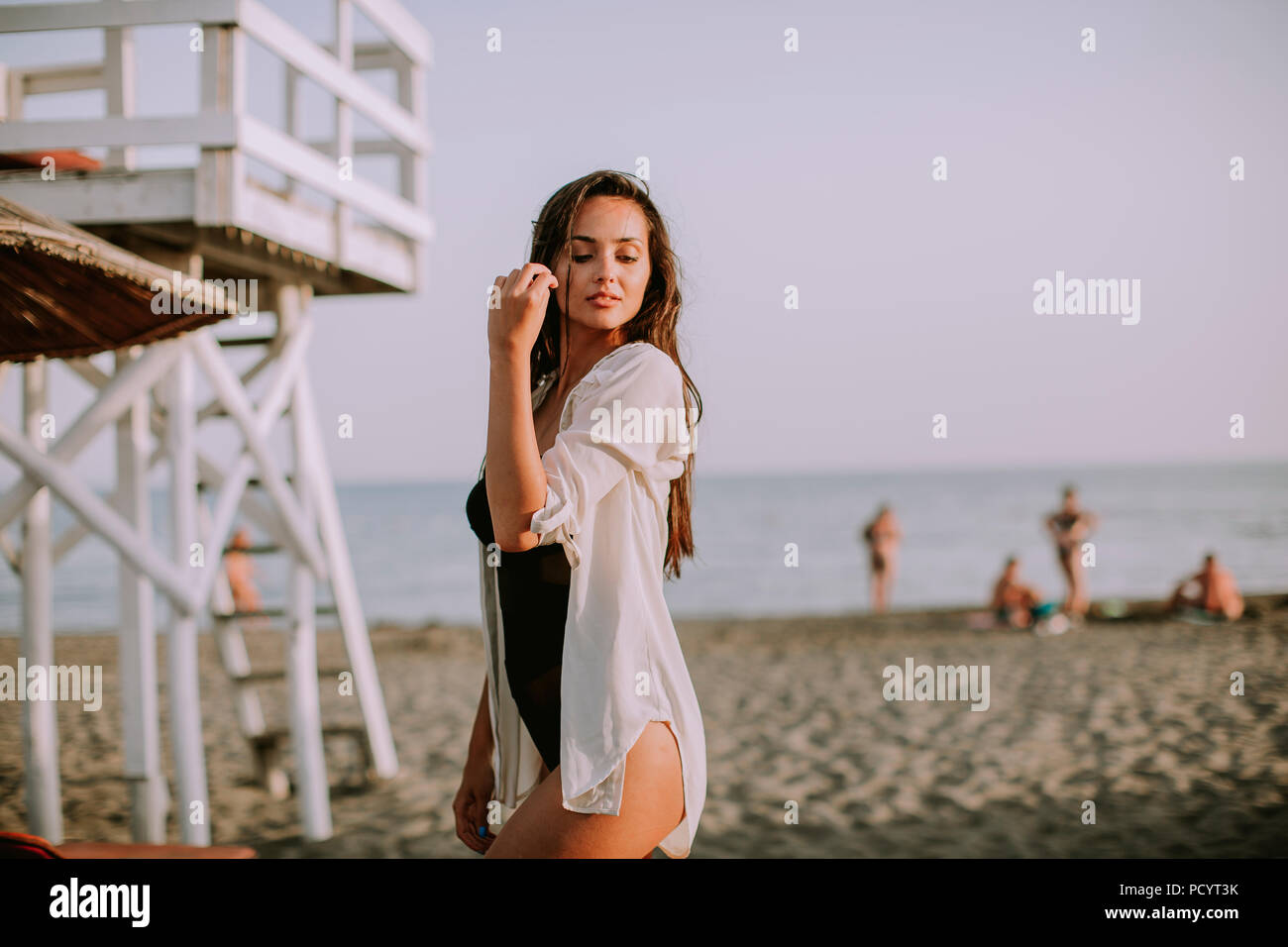 View at young woman posing on the beach by lifeguard observation tower Stock Photo