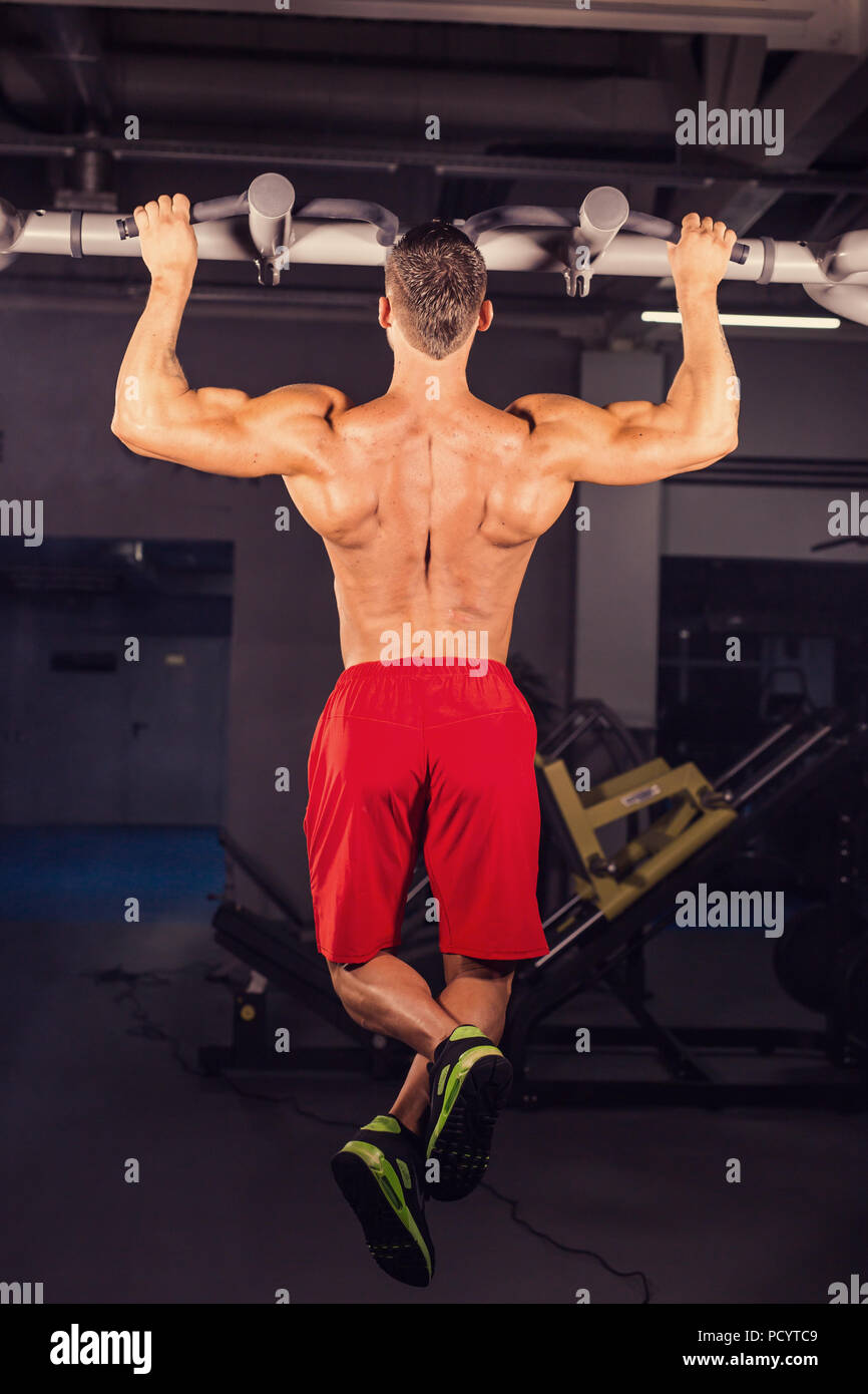 Strong young man doing pull up exercise on horizontal bar in gym Stock ...