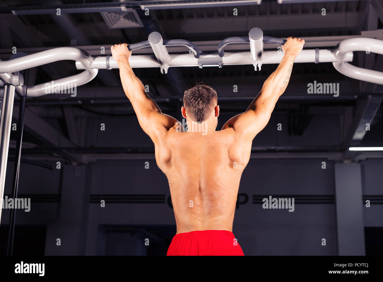 Strong young man doing pull up exercise on horizontal bar in gym Stock ...