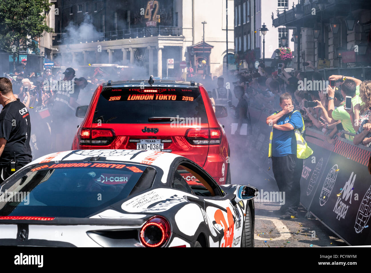 5 Aug 2018 - London, UK. A steward covering nose from smoke. Powerful supercars burning tires at charity race, Gumball Rally 3000. Stock Photo