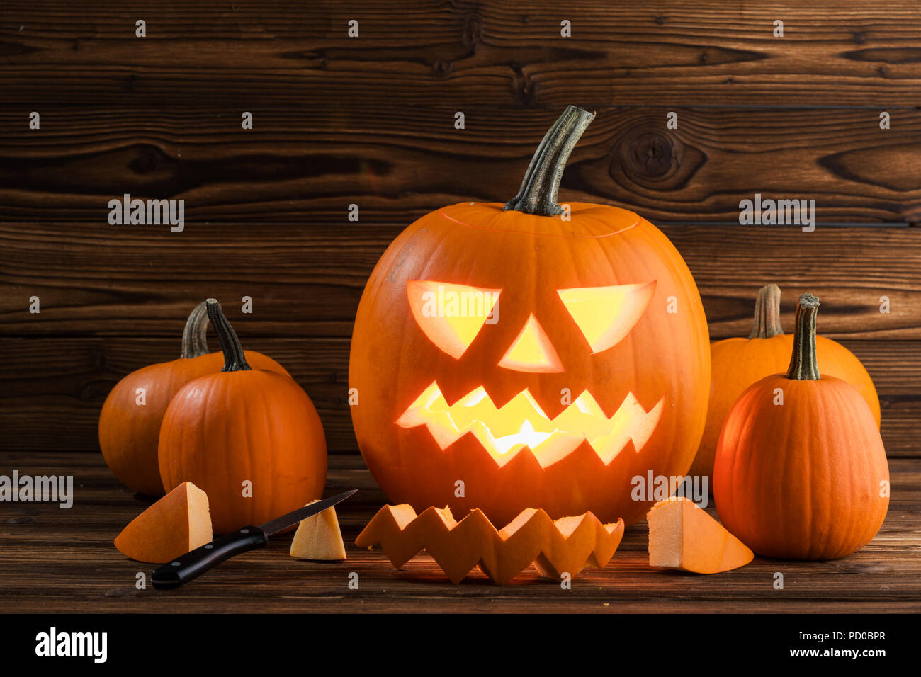 Carving of Halloween pumpkin in progress, pieces and cutting knife on wooden background Stock Photo