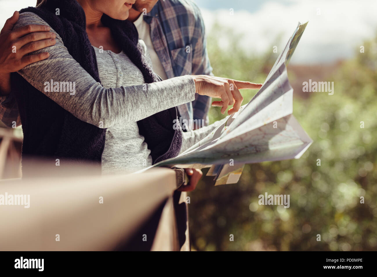 Woman pointing at the map while standing with her boyfriend. Couple looking for travel destination on map. Stock Photo
