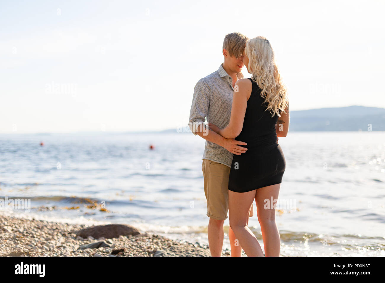 Beautiful young couple in romantic embrace on beach at summer Stock Photo