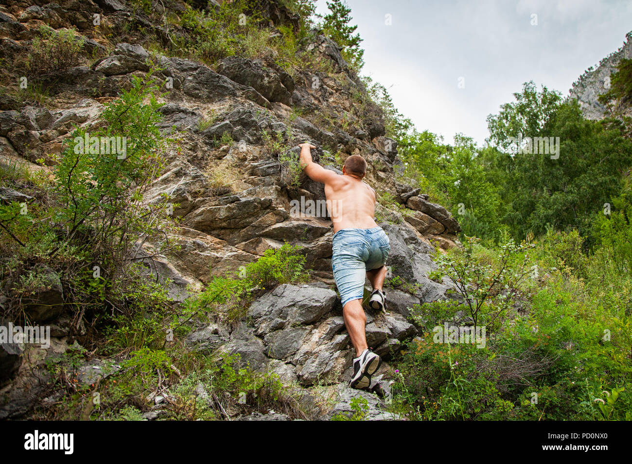 Girl rock climber climbs on the rock with the lower insurance men in  colorful clothes and a hat in the fall Stock Photo - Alamy