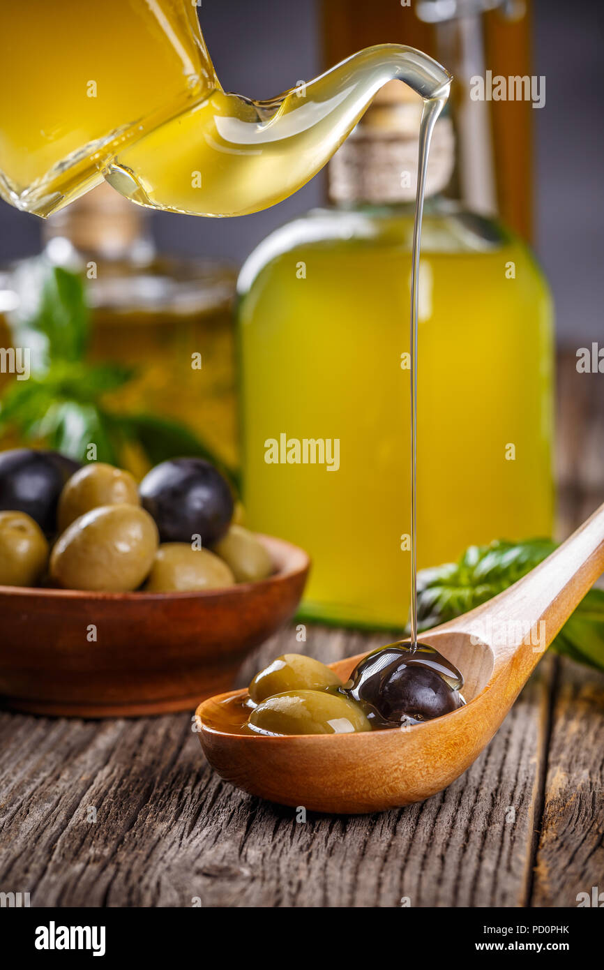 Olive oil pouring over black and green olives Stock Photo
