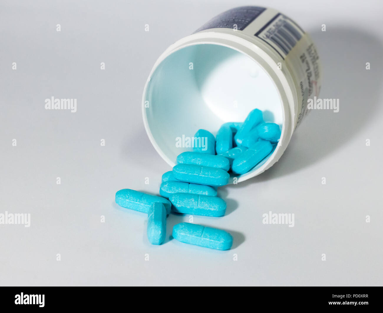 Blue tablets pills spilling from white container Stock Photo