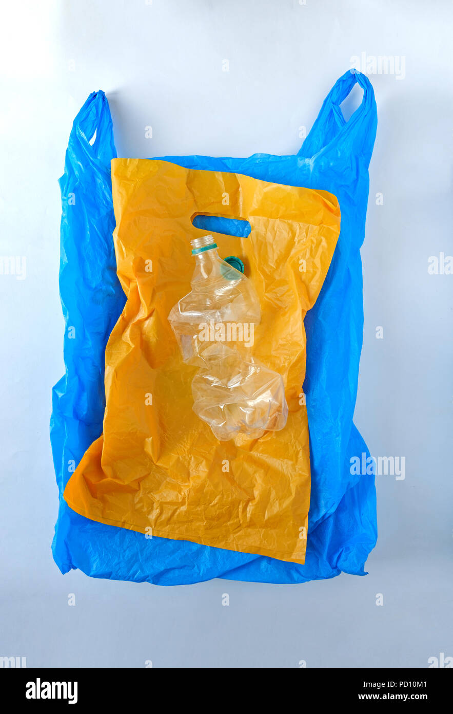yellow and blue plastic bag plastic bottle on a gray background Stock Photo