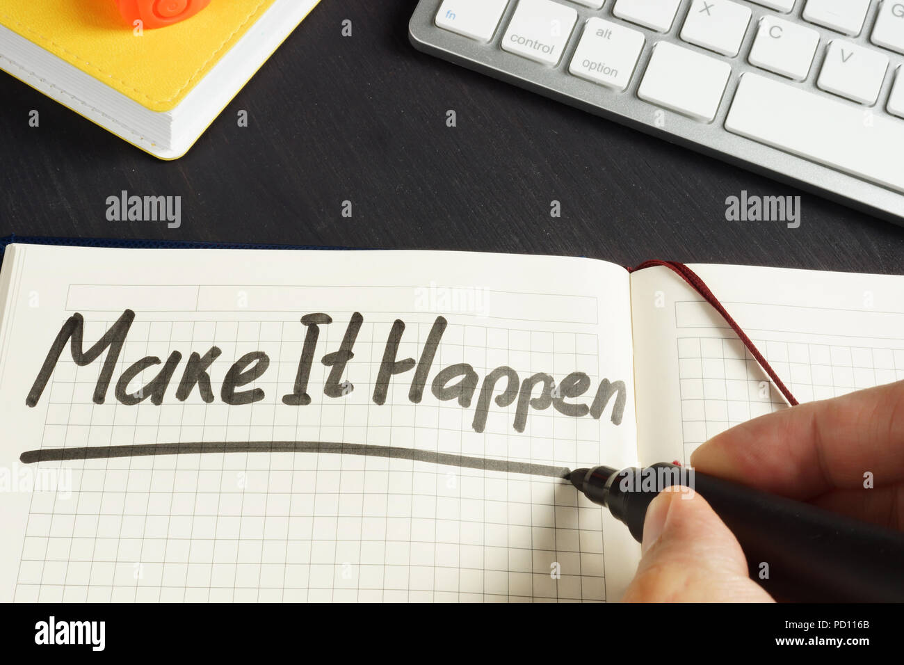 Man is writing Make It Happen in the note. Stock Photo